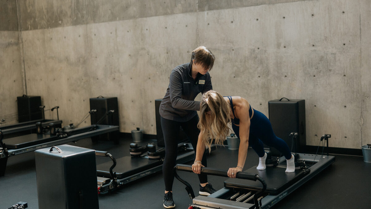 Dr. Karyn providing one-on-one instruction to a pilates student on the reformer.