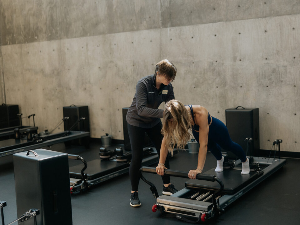 Dr. Karyn providing one-on-one instruction to a pilates student on the reformer.